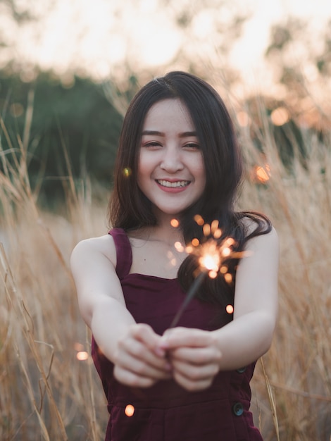 Premium Photo | Happy cute girl holding a sparkler in the dry grass ...