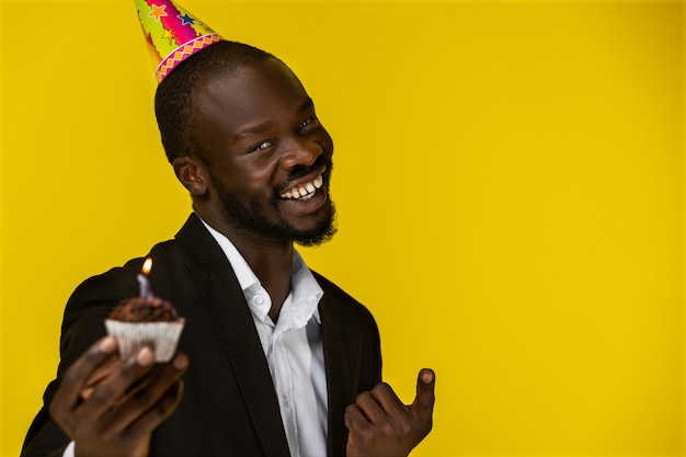 カメラに笑顔と誕生日ケーキを保持している幸せなかわいい黒人 無料の写真