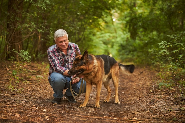 Premium Photo Happy Dog Owner Squatting Next To A German Shepherd While Having A Walk In The Woods