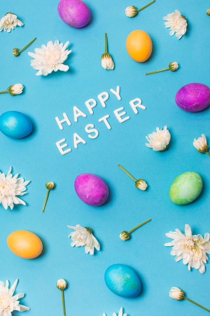 Free Photo | Happy easter title between bright eggs and flower buds