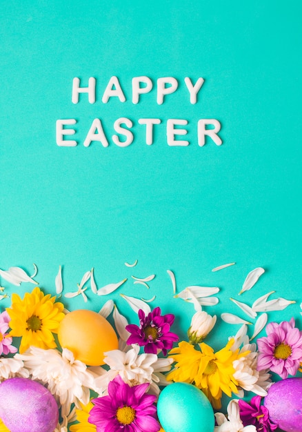 Free Photo | Happy easter words near bright eggs and flower buds