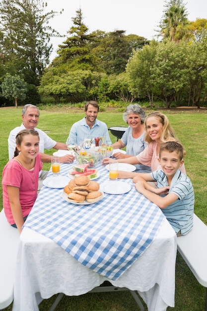Happy extended family having dinner outdoors at picnic table Photo Premium Download