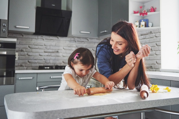 Happy family in the kitchen. holiday food concept. mother and daughter preparing the dough, bake cookies. happy family in making cookies at home. homemade food and little helper Free Photo