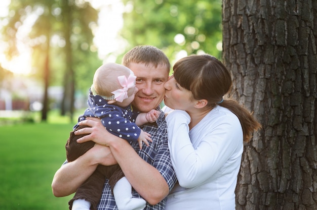 Happy family in the park in spring sunny day kissing of daddy Premium Photo