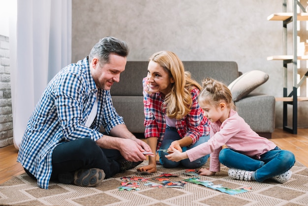 Happy family playing with puzzle pieces with daughter | Free Photo