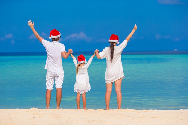 Premium Photo | Happy family of three in santa hats on beach