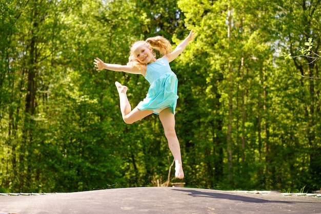 Free Photo | A happy girl in a dress jumps on a trampoline in a park on ...