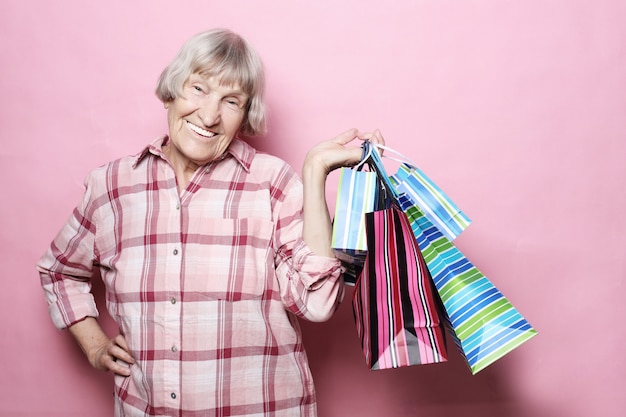 Premium Photo | Happy grandmother with shopping bags over pink