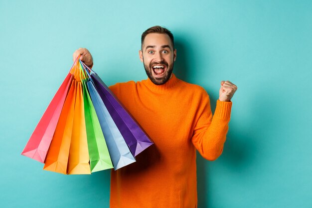 Premium Photo | Happy handsome man holding shopping bags and smiling ...