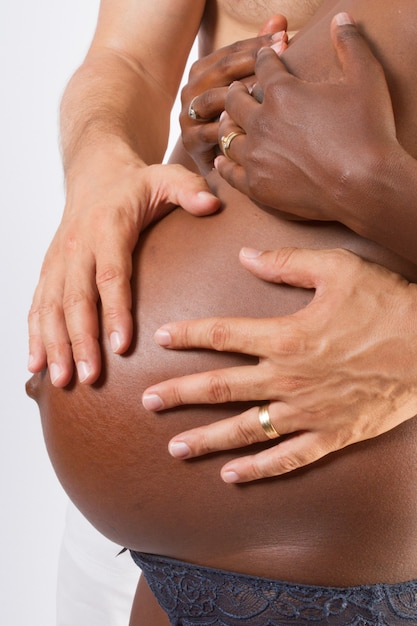 幸せな異人種間のカップル 妊娠中のアフリカ系アメリカ人の妻と白人の夫が赤ちゃんの腹を愛care プレミアム写真