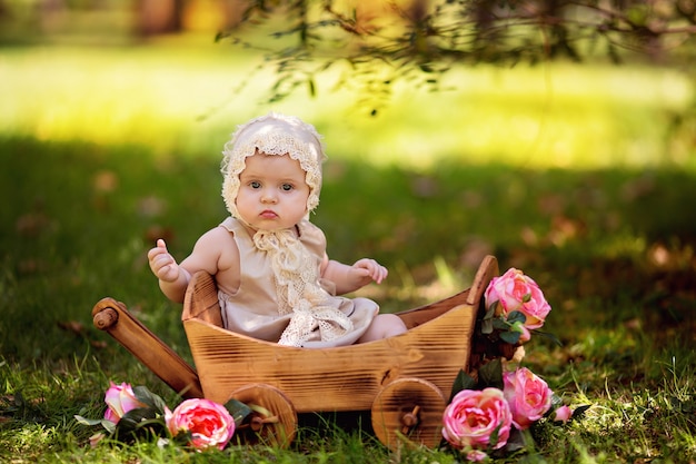 여름에 야외에서 장미 꽃과 함께 장바구니에 행복 한 작은 아기 소녀 프리미엄 사진