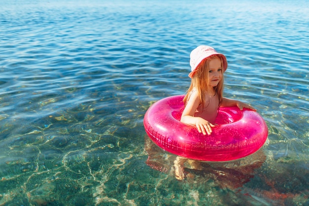 Premium Photo | Happy little girl bathing in sea with pink circle