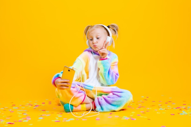 Premium Photo | A happy little girl in a unicorn kigurumi sits on a ...
