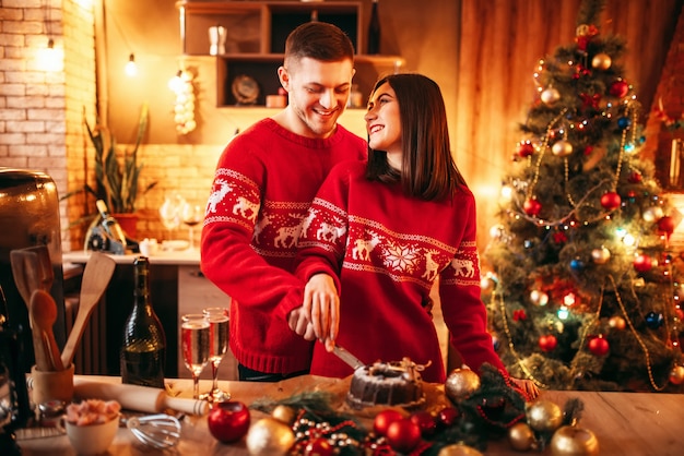 幸せな愛のカップルは クリスマスケーキ お祝い料理を味わいます 一緒にクリスマスのお祝い 若い家族の幸せ プレミアム写真