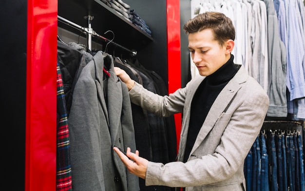 Free Photo | Happy man checking price tag of coat in store