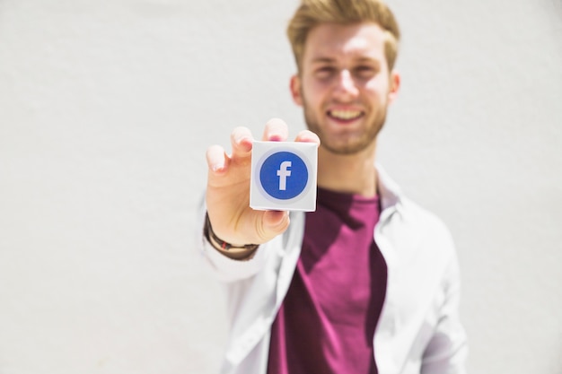 Happy man holding facebook icon cube | Free Photo