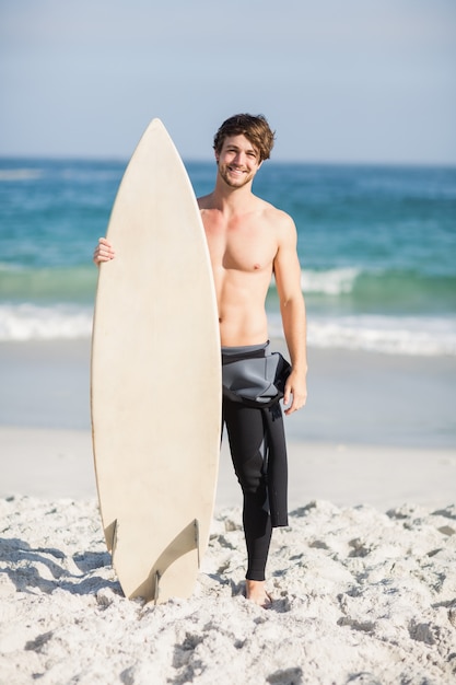 Premium Photo | Happy man holding a surfboard on the beach
