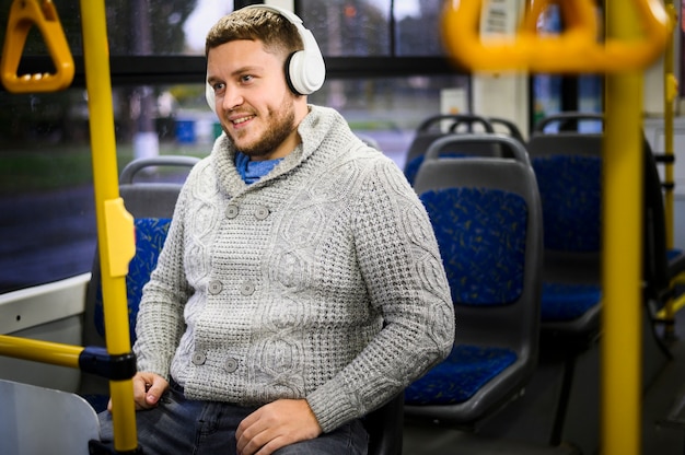 Счастливый человек с наушниками, сидя на сиденье автобуса | Бесплатно Фото