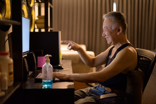 自宅のコンピューターで幸せな成熟した日本人男性ビデオ通話 プレミアム写真