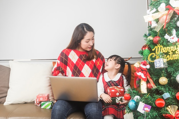 幸せな母と小さな娘が家でクリスマスツリーとギフトを飾る 無料の写真