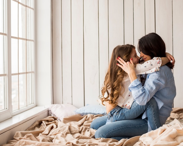 Free Photo Happy Mother And Daughter Hugging On Bed 