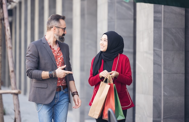 Happy muslim woman and boy freind with city shopping hand holding paper bags Premium Photo