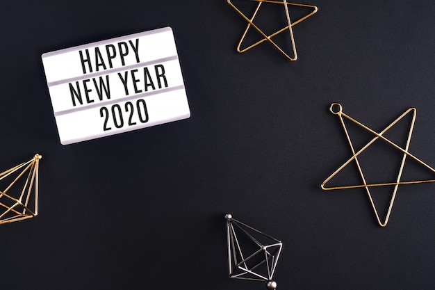 Happy new year 2020 party light box with star decoration item top view on black background table Premium Photo