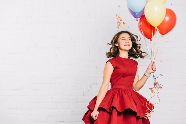 Happy portrait of a teenage girl holding balloons in hand jumping Free Photo