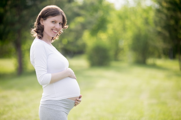 Happy pregnant woman on late pregnancy stage posing in park | Free Photo