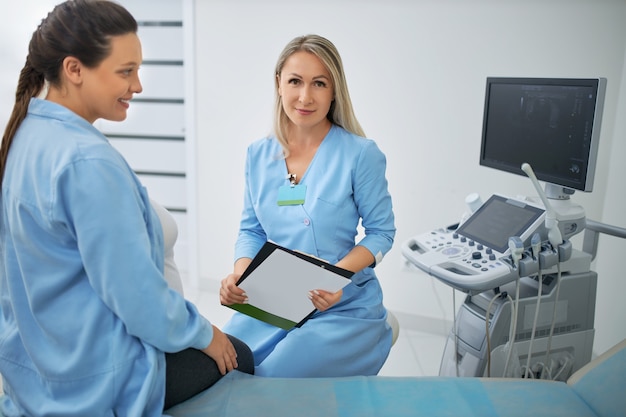 Premium Photo Happy Pregnant Woman With Dark Hair Having Regular Medical Examination With Female Doctor At Modern Clinic Gynecology Consultation