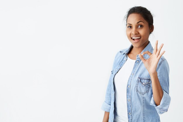 Happy satisfied afro-american female wearing denim shirt making ...