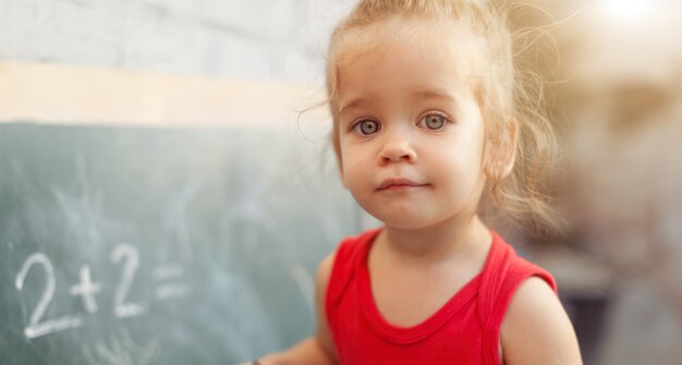 Happy school girl on math classes in kindergarten finding solution and solving problems Premium Photo