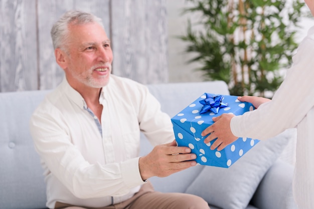 Free Photo | Happy senior man sitting on sofa receiving gift front a boy