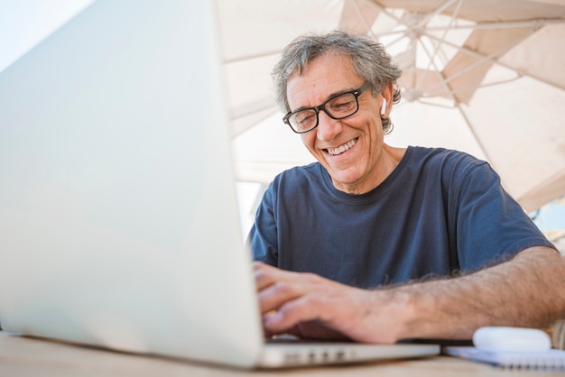 Happy senior man wearing eyeglasses using laptop at outdoor caf� Free Photo