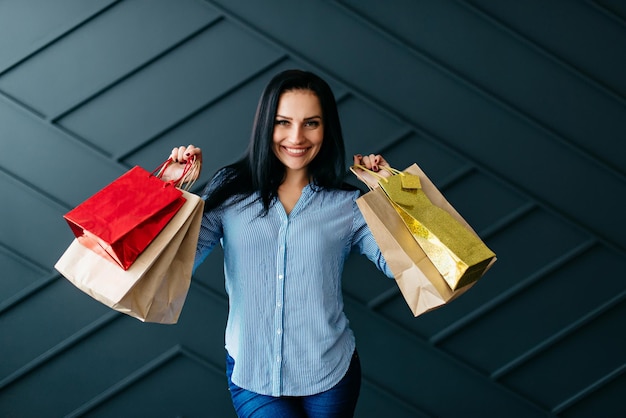 Premium Photo Happy Woman Holding Shopping Bags In Hands On Black Wall