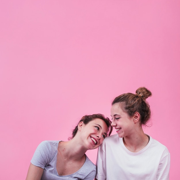 Free Photo | Happy woman leaning on woman's shoulder over pink background