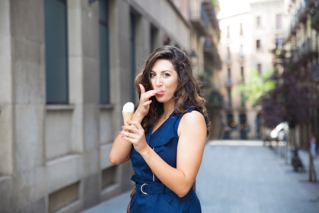 アイスクリームを食べながら指をなめる幸せな女性 無料の写真