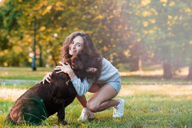 庭で彼女の犬を愛している幸せな女性 無料の写真