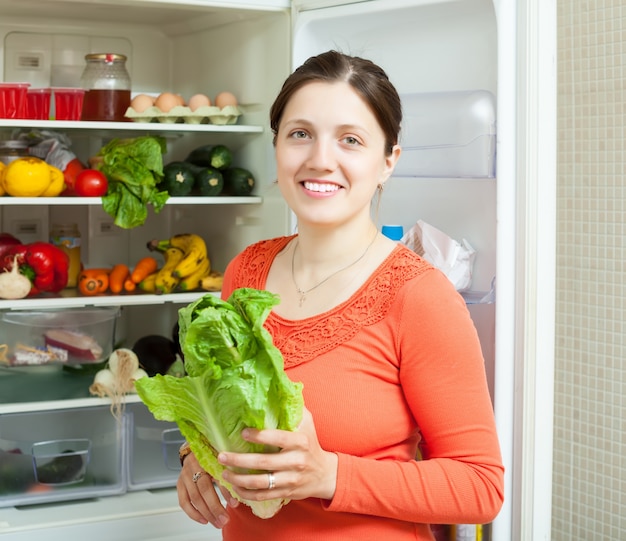 Happy woman putting vegetables into refrigerator Free Photo