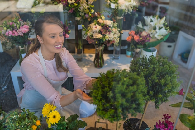 Premium Photo | Happy woman taking care of flowers in flower shop