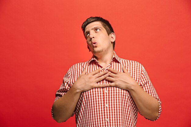 Happy worried man posing over red wall. Free Photo