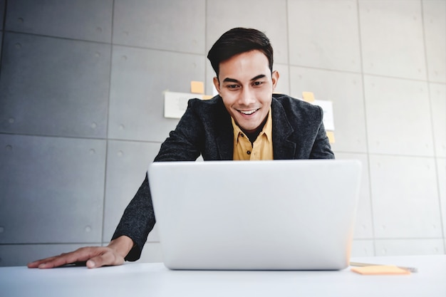 Happy young asian businessman working on computer laptop in office ...