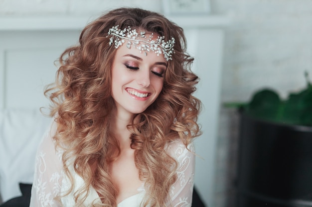 Happy young bride in tiara and lingerie laughing. Close portrait. Free Photo