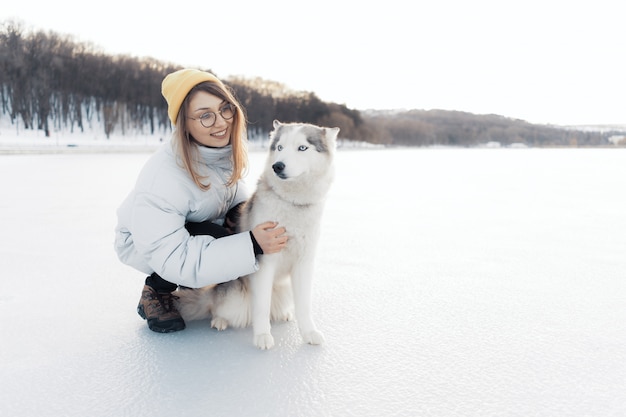 無料の写真 冬の公園でシベリアンハスキー犬と遊んで幸せな若い女の子