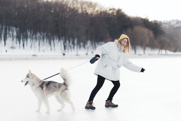 無料の写真 冬の公園でシベリアンハスキー犬と遊んで幸せな若い女の子