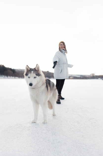 無料の写真 冬の公園でシベリアンハスキー犬と遊んで幸せな若い女の子