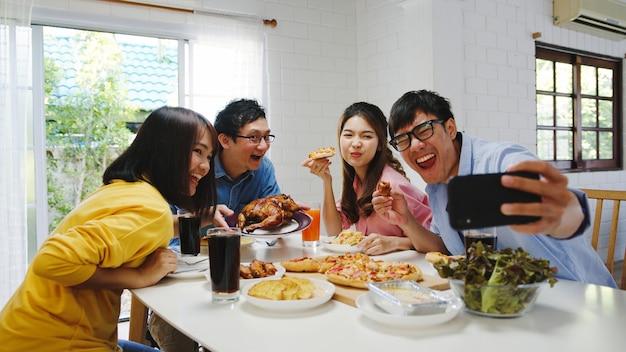 Happy young group having lunch at home. asia family party eating pizza food and making selfie with her friends at birthday party at dining table together at house. celebration holiday and togetherness Free Photo