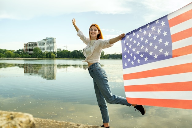 Happy young woman with united states national flag in her hand. positive girl celebrating us indepen