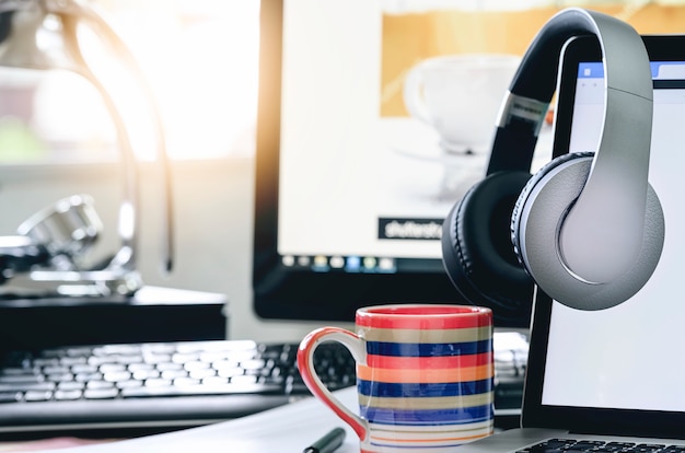 Premium Photo | Headphones hang on laptop monitor with blank screen.