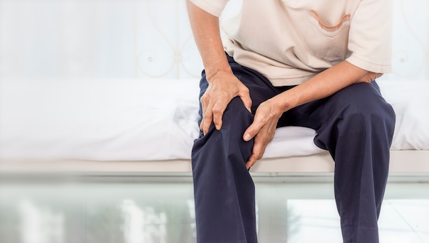 Health problem concept; old woman suffering from knee pain at home. Premium Photo